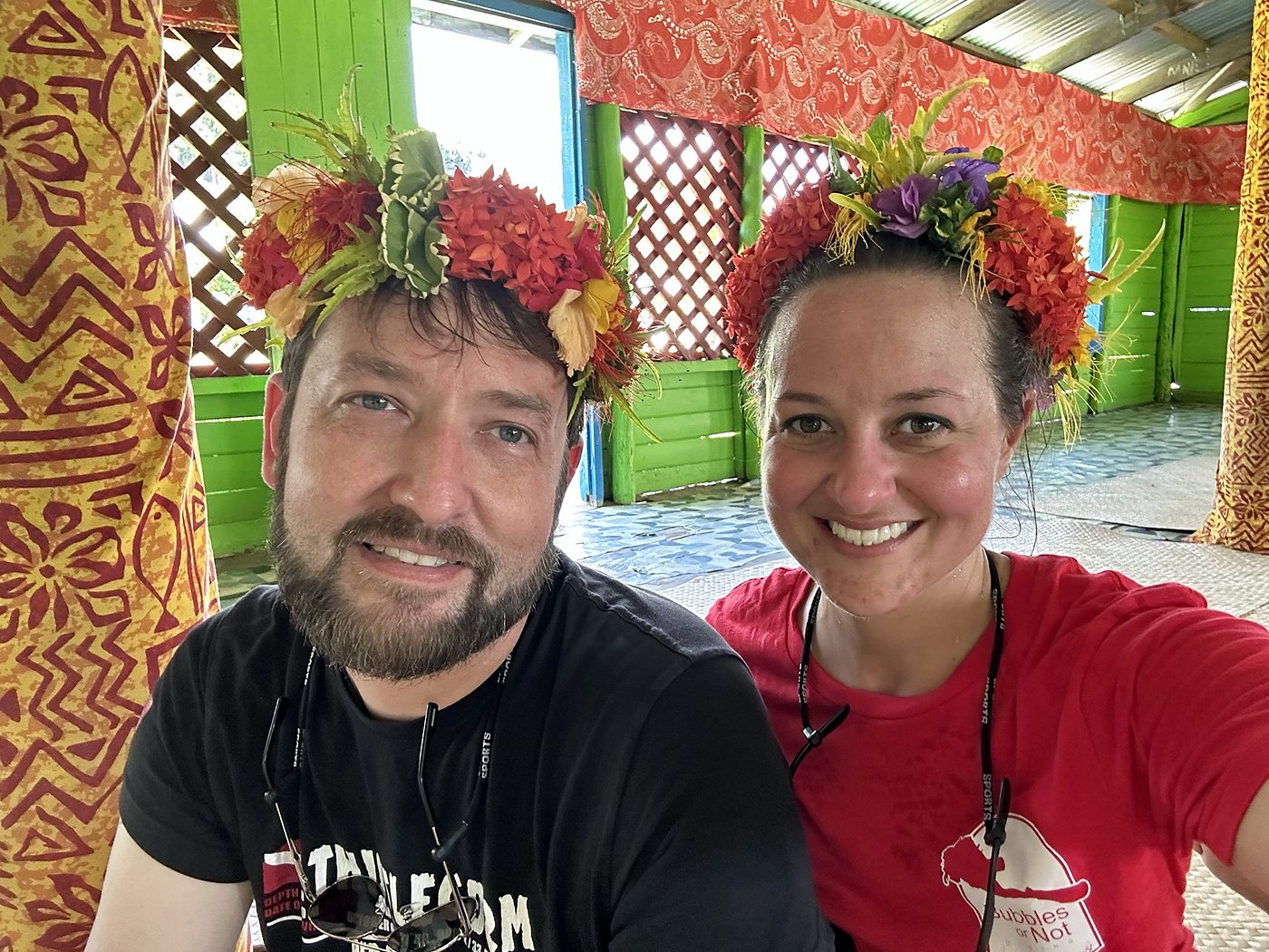 Eric and Allie in flower crowns in a Fijian village hall