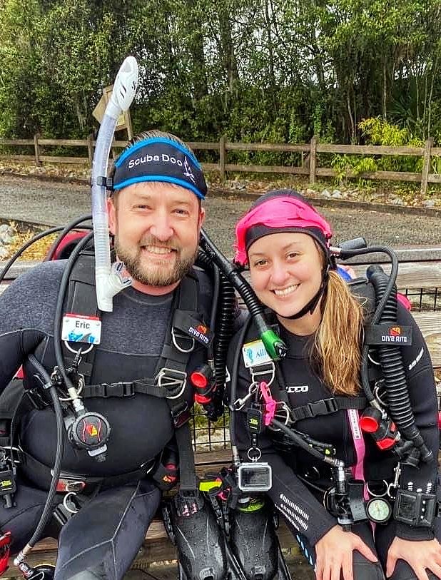 Eric and Allie in full dive kit on the bench at the dive park, February 2022